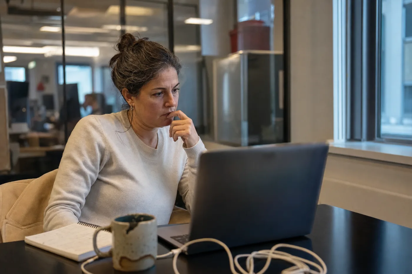 A hiring manager studying a candidate closely during a remote video interview, the moment deepfake security awareness training is meant to prepare her for
