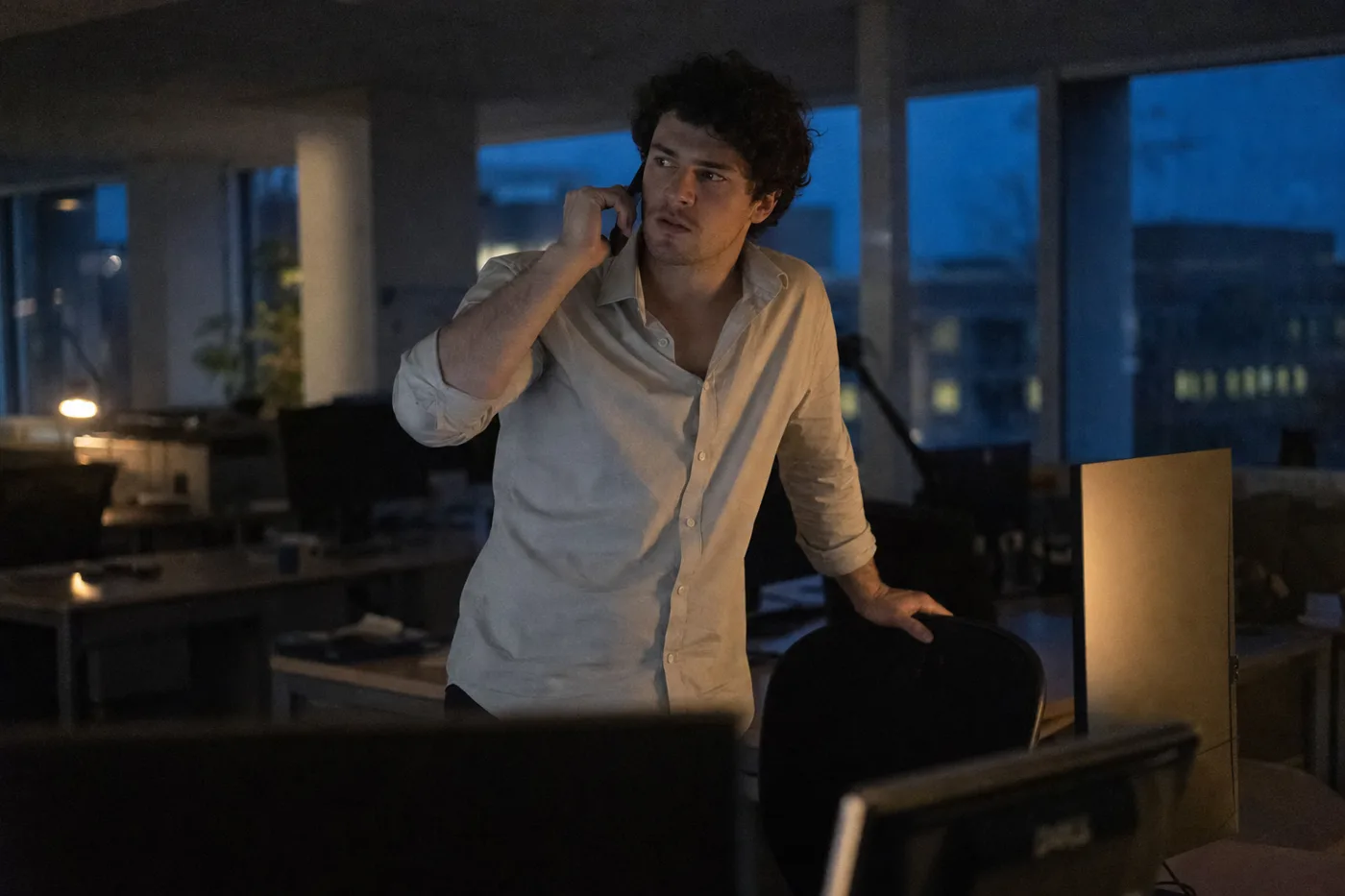 An employee working late, verifying a suspicious request by calling back on a known number rather than trusting what he saw on screen