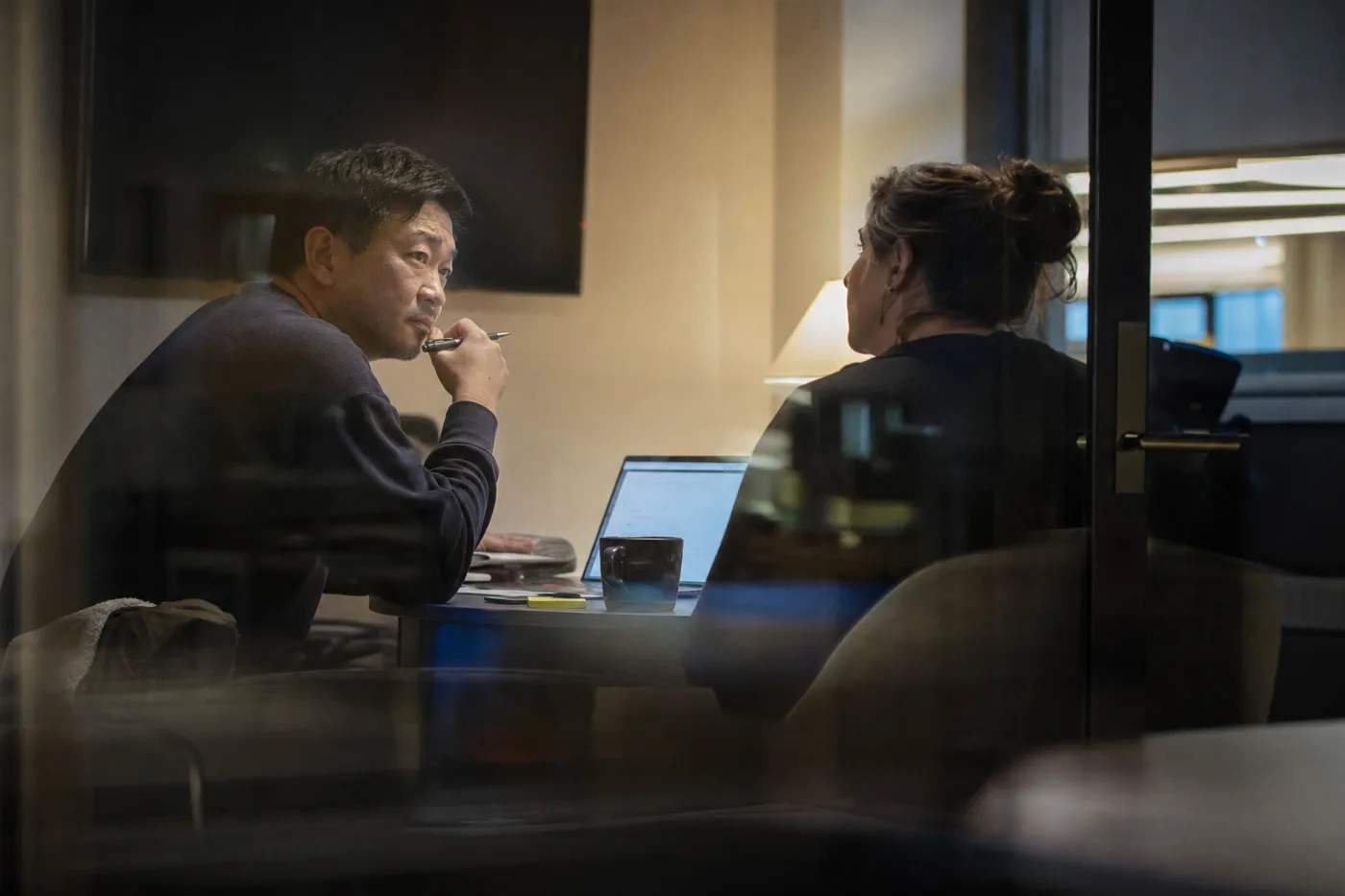 Two coworkers rehearse a difficult one-on-one conversation in a glass meeting room during first-time manager training