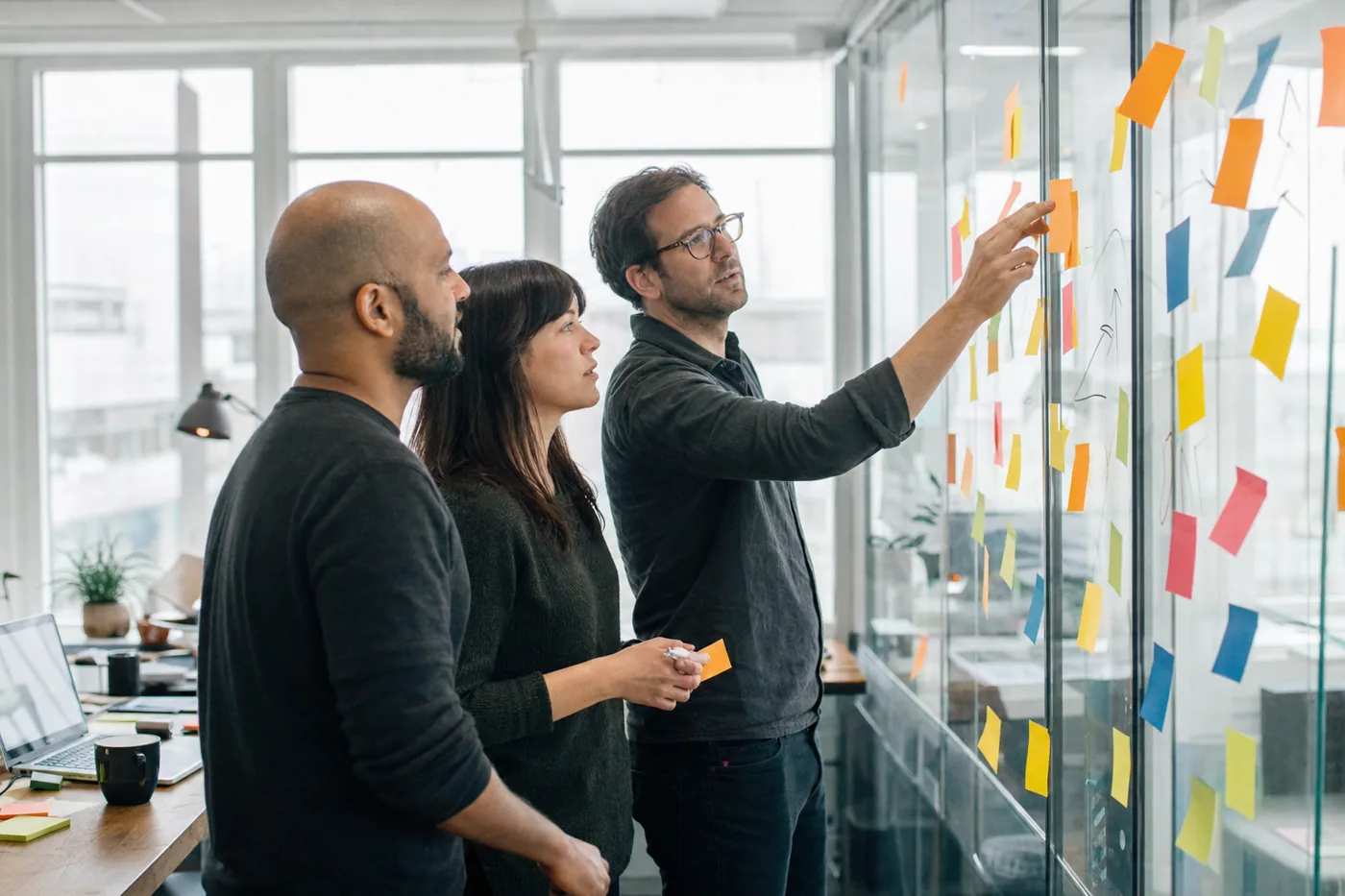 An L&D team mapping out a skills-based training program on a glass wall covered in sticky notes in a bright modern office